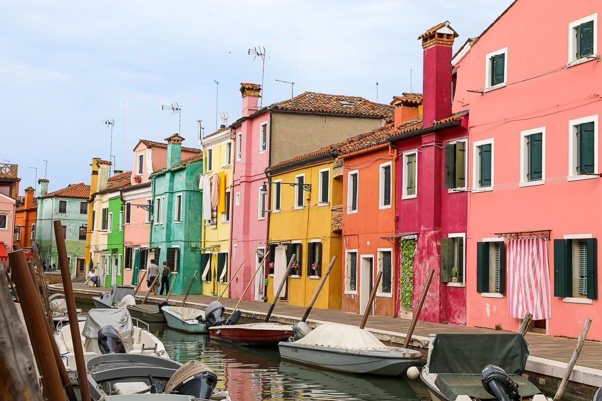 Colorful houses lining up a canal in Burano, Venice. Take a virtual tour of Murano and Burano in this guide!