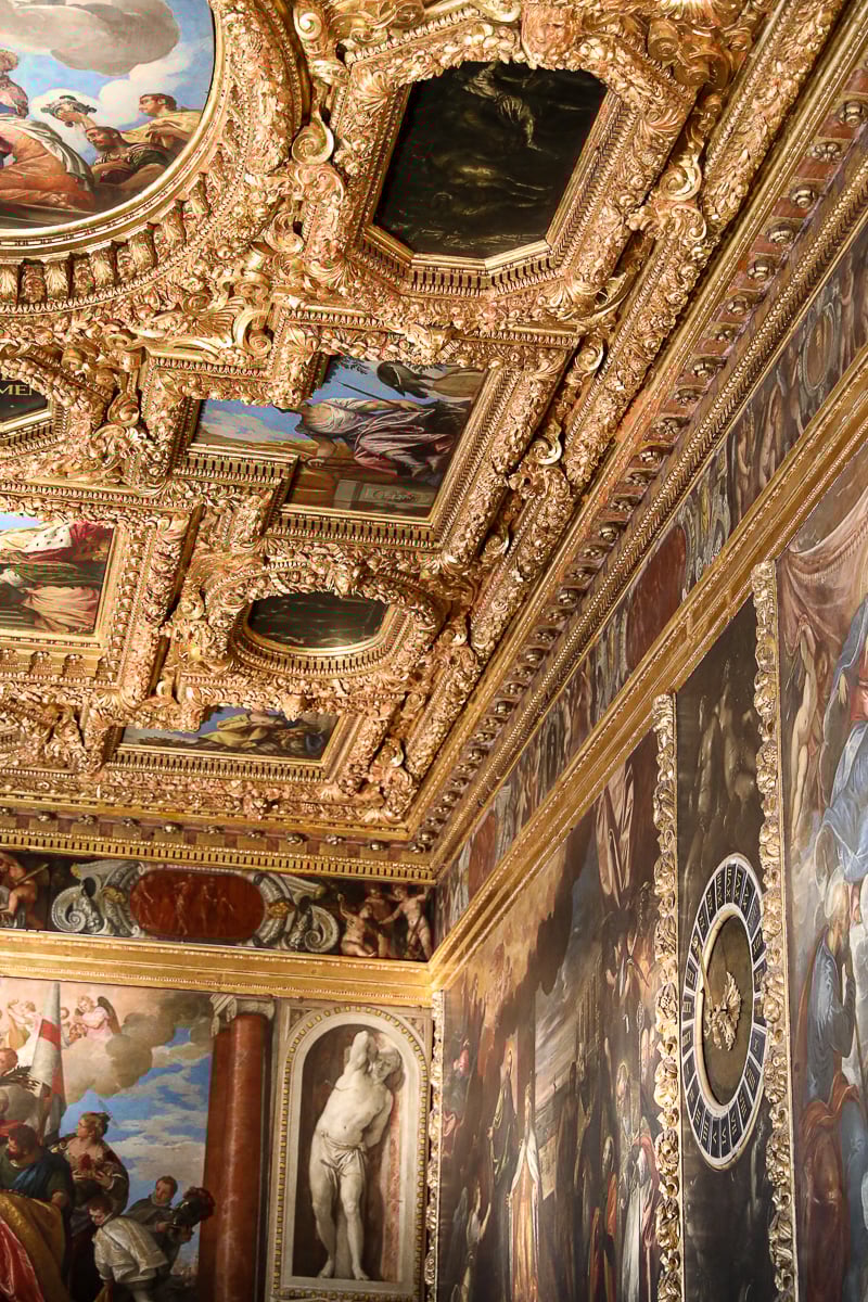 An opulent room, decorated with gold molding and frescoes, inside of Doge's Palace